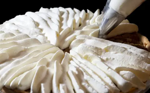 Garniture d'une tarte avec une poche à douille, évoquant la recette crémeux vanille Michalak.
