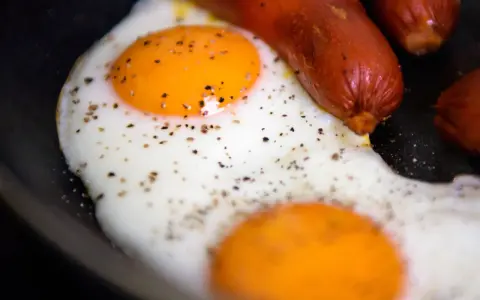 Due uova occhio di bue con pepe nero e salsicce in padella.