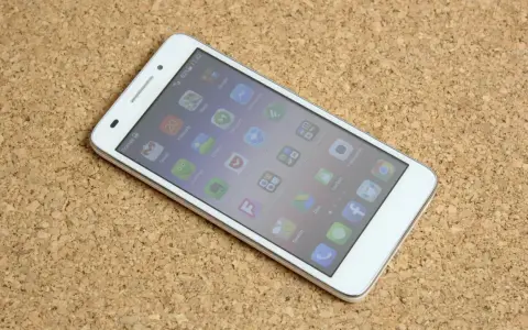 Biały smartfon Huawei G620S leżący na korkowym tle, z widocznym ekranem głównym.