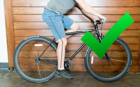 A cyclist demonstrates proper bike seat height with a slight knee bend at the bottom of the pedal stroke. A green checkmark confirms the correct adjustment.