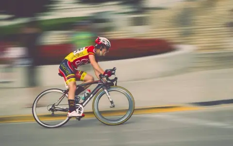 Kolarz w żółto-czerwonym stroju pędzi na rowerze. Ile czasu zajmie mu pokonanie 50 km na rowerze?