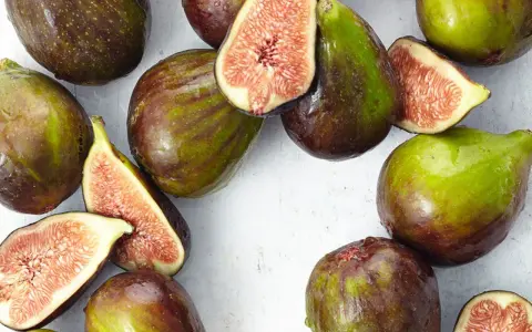 Frische Feigen, teils angeschnitten, zeigen ihr saftiges Inneres. Man fragt sich, wie schmecken feigen wohl? Süß und honigartig.