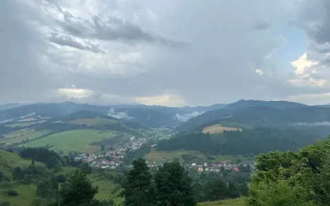 Widok na dolinę z wioską i górami w tle, chmury nad przełęczą pod Tokarnią.