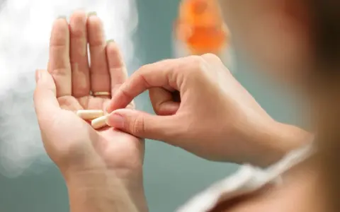 Dłoń trzyma kapsułki, które mogą być lekami do hormonalnej terapii zastępczej.