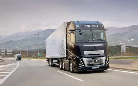 Camión Volvo FH Aero 780 negro con remolque blanco avanza por una carretera montañosa.