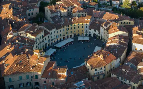 Vista aerea di Piazza dell'Anfiteatro a Lucca, perfetta per un weekend indimenticabile tra tetti rossi e vita cittadina.