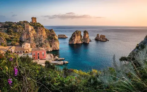 Traumhafte Küstenlandschaft mit Felseninseln, einem alten Turm und einem roten Haus. Perfekt für ein Auslandsjahr in Italien.