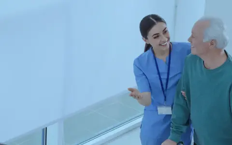 Enfermera sonriente ayuda a un anciano a caminar. El **fp tcae** de la atención médica se refleja en su mirada.