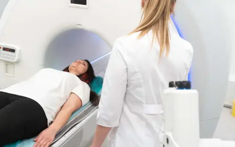 Patient liegt auf dem Tisch für die pelottierung des duralschlauches. Eine Ärztin in weißem Kittel überwacht den Vorgang.