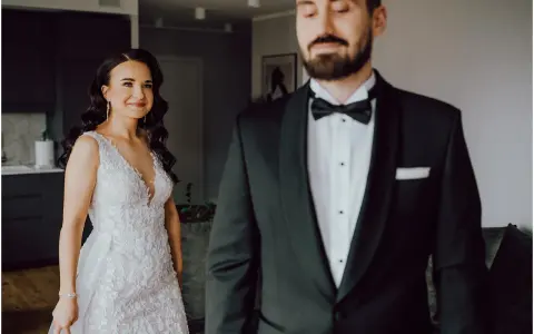 Piękna panna młoda w koronkowej sukni i pan młody w smokingu. Kameralna atmosfera idealna, by poczuć magię pierwszego spojrzenia.