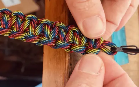 Mani che chiudono un braccialetto colorato con filo, mostrando come chiudere un braccialetto con filo.