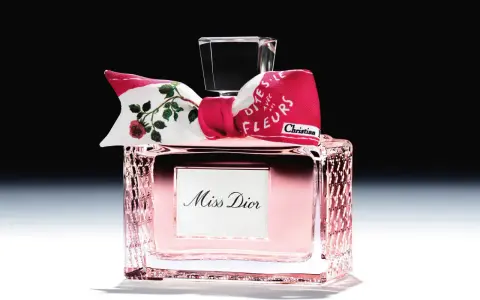 Eleganckie perfumy Miss Dior w różowym flakonie, ozdobione kokardką z motywem róż i napisem "Dites-le avec des fleurs".