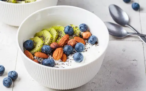 Schüssel mit Magerquark, Blaubeeren, Kiwi, Mandeln und Chiasamen. Perfekt für gesunde Magerquark Rezepte.