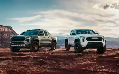 Dwa nowe modele toyota pickup, biały i szary, gotowe na przygodę w surowym, pustynnym krajobrazie.