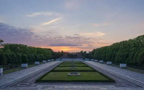 Sonnenuntergang über dem Sowjetischen Ehrenmal in Berlin. Ein beeindruckendes Beispiel für Parks in Berlin, mit symmetrischen Rasenflächen und einer langen Allee.