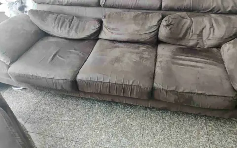 Divano marrone con cuscini un po' affossati, pronti per rifare imbottitura cuscini divano e ridargli vita.
