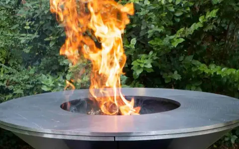 Un moderno braciere da giardino, con fiamme vivaci che danzano al centro, crea un'atmosfera accogliente.