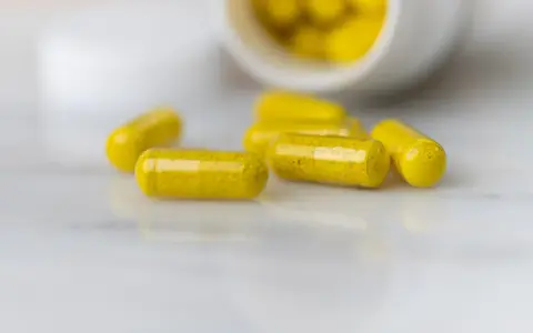Capsule gialle sparse su una superficie chiara. La berberina a cosa serve? Potrebbe essere la risposta in queste capsule.