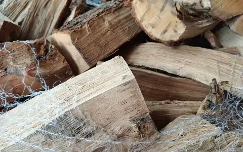 Gros plan sur un poids stère de bois sec, emballé dans un filet blanc, prêt pour l'hiver.