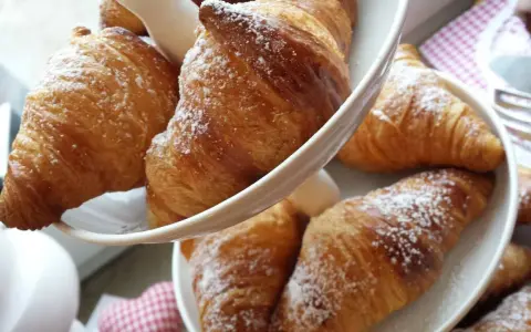 Cornetti fatti in casa, dorati e spolverati di zucchero a velo, invitano a una colazione golosa.