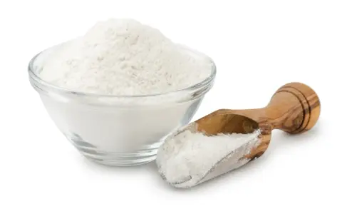 Una ciotola di vetro piena di polvere bianca, probabilmente aluminum starch octenylsuccinate, e un cucchiaio di legno con la stessa polvere.