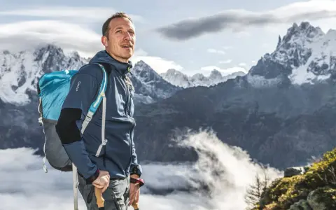 Randonneur contemplant les montagnes, son sac à dos léger prêt pour l'aventure.