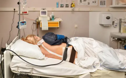 Pacjentka w łóżku szpitalnym, podłączona do aparatury. Znieczulenie w kręgosłup skutki uboczne mogą być różne, ale tu skupiamy się na monitorowaniu.