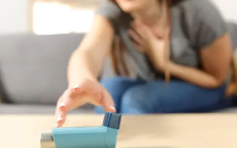 Kobieta z atakiem astmy sięga po inhalator z fenoterolem.
