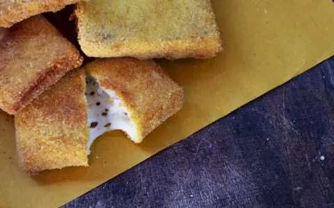 Mozzarella in carrozza dorata e croccante, con il formaggio filante che fuoriesce da uno dei pezzi.