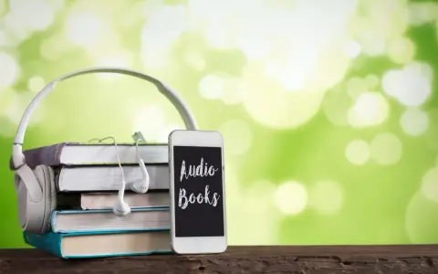 Słuchawki, stos książek i telefon z napisem "Audio Books" – idealne połączenie do odkrywania najpiękniejszych słuchowisk dla dzieci.