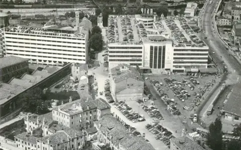 Vista aerea del parcheggio San Andrea a Venezia, con file di auto parcheggiate su più livelli e un edificio INA.
