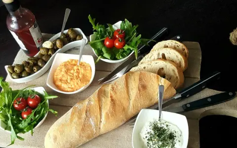 Eine köstliche italienische Brotzeit mit Baguette, Oliven, Tomaten, Rucola und Dips.