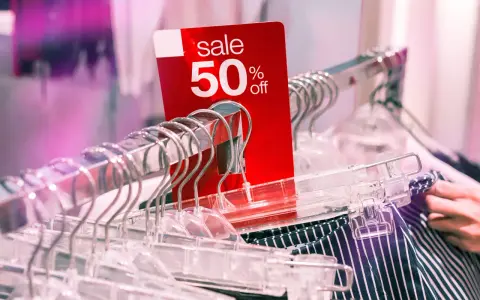 Czerwona metka "sale 50% off" na wieszakach. Czy to początek kompulsywnych zakupów?