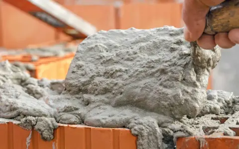 Łopata z zaprawą murarską na cegłach. Czas schnięcia zaprawy murarskiej zależy od wielu czynników.