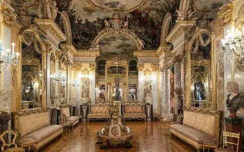 Złocone wnętrze pałacowe, przypominające muzeum w Madrycie, z malowidłami na suficie i bogatymi zdobieniami.