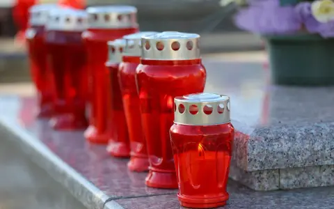 Rote Grablichter brennen auf einem Grabstein. Am 1. November, dem Feiertag Allerheiligen, werden sie zum Gedenken entzündet.