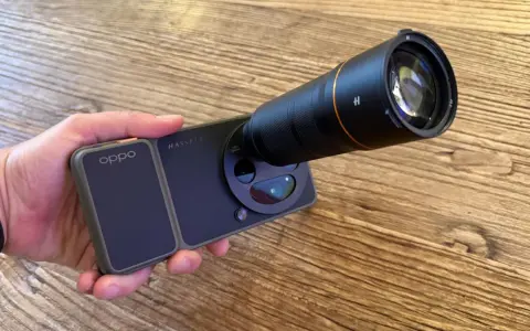 Mano sujetando un teléfono **cámara Oppo** con un gran lente acoplado, listo para capturar imágenes detalladas.
