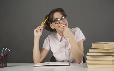 Ragazza con occhiali e matita gialla, un libro aperto e pile di libri, un'espressione pensierosa che ricorda l'anastrofe figura retorica.
