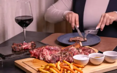 Idealne wino do dziczyzny? Czerwone, pełne, jak to w kieliszku obok soczystego steka i frytek. Ktoś kroi kolejny kawałek.