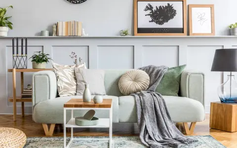 Un plaid gris drapé sur un canapé vert menthe, ajoutant une touche cosy. Idée pour comment mettre un plaid sur un canapé.