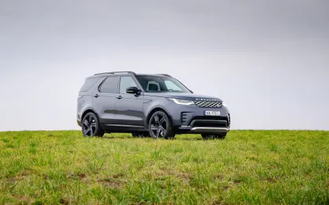 Szary Land Rover Discovery stoi na zielonej łące.