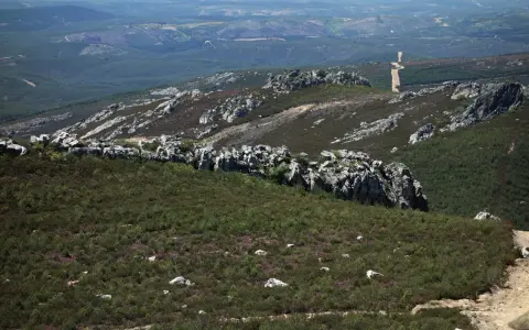 Paisaje rocoso y verde en la sierra de la Culebra, con vegetación baja y un camino serpenteante al fondo.