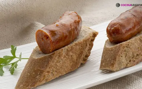 Chorizo a la sidra jugoso sobre pan rústico, decorado con perejil fresco. Un bocado delicioso.
