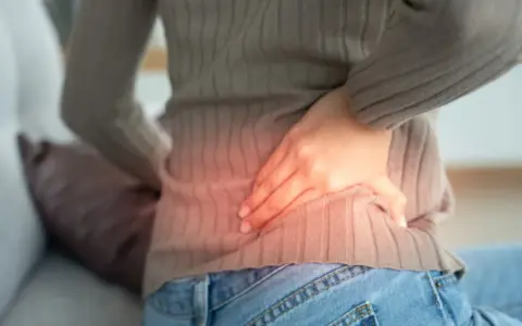Kobieta z bólem w boku, wskazującym na możliwe przyczyny pomniejszonej nerki.