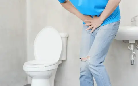 Mężczyzna w łazience czuje ból przy oddawaniu moczu. Szuka domowych sposobów na pieczenie.