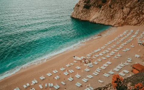 Piękna plaża z rzędami leżaków i turkusową wodą. Idealne miejsce, gdzie do Turcji na wakacje.