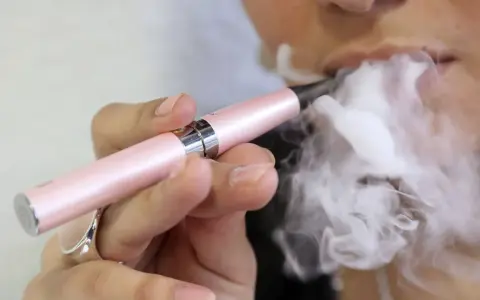 Persona vapea con un dispositivo rosa, liberando vapor. ¿Qué pasa si fumas vaper con nicotina?