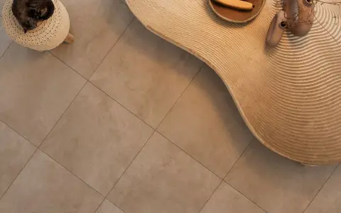 Kot śpi na pufie, obok falistego stolika z bananami i wazonami. Podłoga z gres lappato czyszczenie jest nieskazitelna.