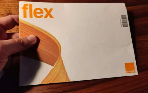 Dłoń trzyma kopertę z napisem "flex" i logo Orange. To oferta Orange Flex.