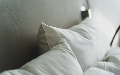 Cojines blancos sobre una cama, perfectos para conocer las medidas de cojines para cama de 150.